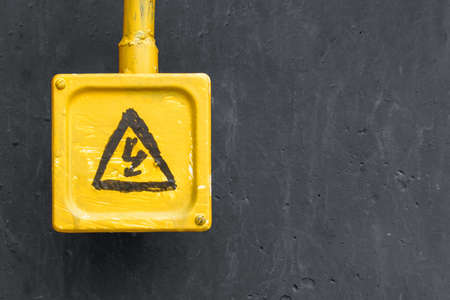 Yellow danger sign on the grey wall