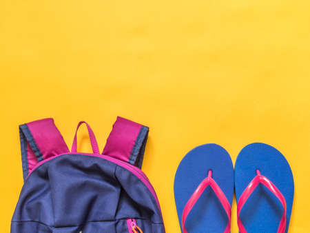 Travel vacation background. Flip flops, backpack on a yellow background. Flat layの写真素材