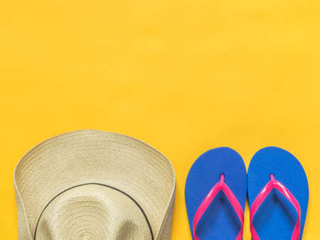 Travel vacation background. Flip flops, hat on a yellow background. Flat layの写真素材