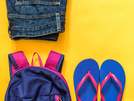 Travel vacation background. Flip flops, backpack, jeans on a yellow background. Flat layの写真素材