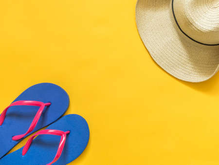 Travel vacation background. Flip flops, hat on a yellow background. Flat lay