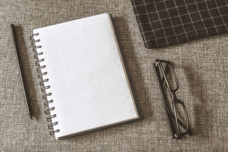 Top view goals list with notebook, pencil, glasses on grey fabric. Flat lay, copy spaceの写真素材
