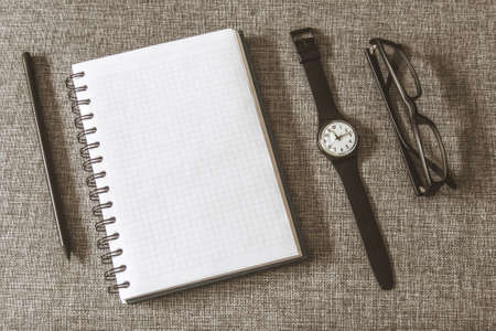 Top view goals list with notebook, pencil, glasses on grey fabric. Flat lay, copy spaceの写真素材
