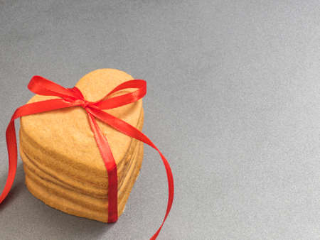 Homemade ginger biscuits in the shape of a heart tied with a red ribbon. Gift