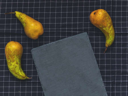 Three green pears Conference, a cutting board slate on black cloth with blank space for text. Flat...