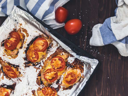 Chicken fillet baked with tomatoes and cheese on a baking sheet with foil. Delicious healthy food....
