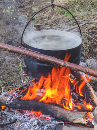 Tourist pot hanging on the fire. Fish soup