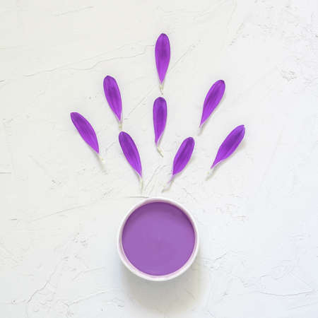Purple cosmetic cream and purple flower petals on white background. Creative beauty fashion cosmetics photo. Flat layの写真素材