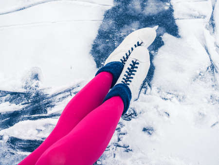 Winter holidays, weekends, fun. Beautiful female legs in bright pink tights and white ice skates....