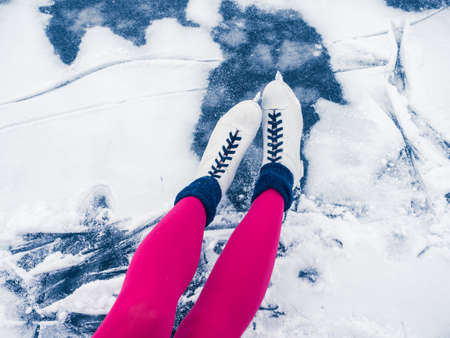 Winter holidays, weekends, fun. Beautiful female legs in bright pink tights and white ice skates....