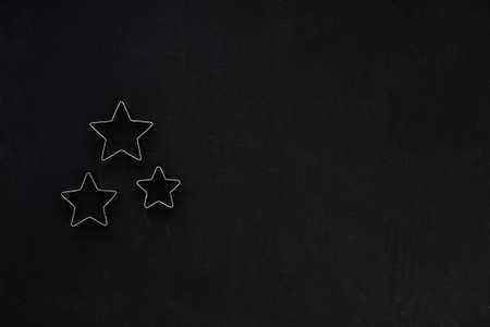Metal stars on black festive background. Baking molds. Cookie cutters. Flat lay, top viewの写真素材
