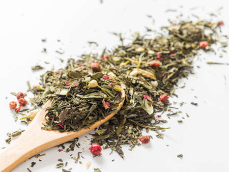 Dry leaves of Sencha green flower tea with cowberry leaf, red currant, Jasmine, rose petals, honey granules, forest berry aroma on white backgroundの写真素材
