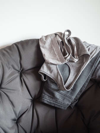 Gray womens clothing on a gray chair. Shirt, jeans. Neutral backgroundの写真素材