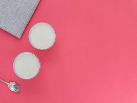 Healthy breakfast. Yogurt in white glasses on pink background. Copy space, flat lay, top viewの写真素材
