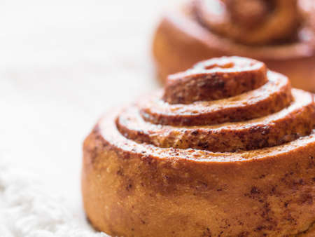 Confectionery baking. Sweet fresh soft roll bun with cinnamon on white background. Cinnabon closeup