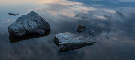Calm, serenity, meditation concept. Sunset on the lake, stones in the water in the foreground, quiet...
