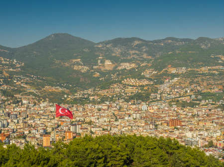 Alanya, Turkey. Beautiful view from the fortress Alanya Castle of the turkish flag on the background of the city of Alanya. Vacation postcard backgroundの写真素材