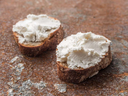 Whole grain bread bruschetta with white soft curd cream cheese on a ginger grunge background. Close-up.の写真素材