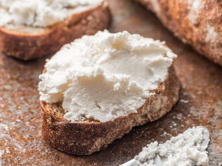 Whole grain bread bruschetta with white soft curd cream cheese on a ginger grunge background....