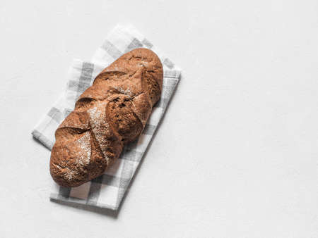 Loaf dark buckwheat bread on white textile napkin white table background. Fresh delicious homemade healthy bake. Bakery. Top view. Copy space.の写真素材