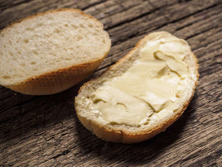 Slice of white bread with butter on a wooden board. Top view. Close-upの写真素材