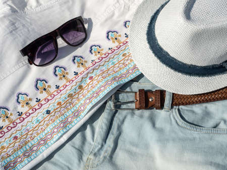 Flat lay fashion women summer beachwear accessories: sunglasses, shirt, hat, belt. Travel vacation background. Top viewの写真素材