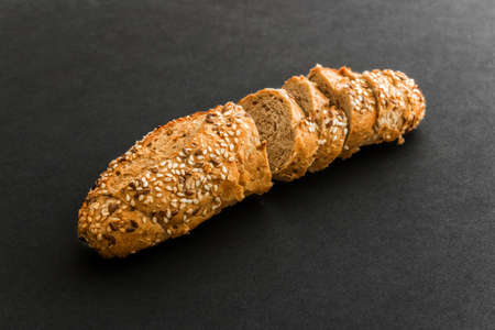 Wholegrain sliced freshly baked bread with flax and sesame seeds on black background. Top view.の写真素材