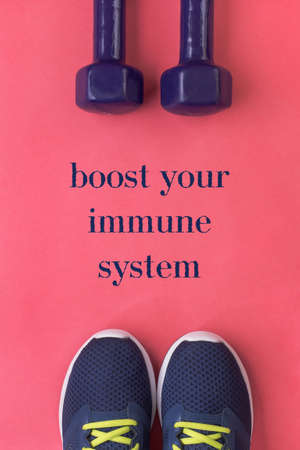 Boost your immune system poster - sports and active lifestyle concept. Purple running shoes and two dumbbells on pink background. Flat lay. Top viewの写真素材