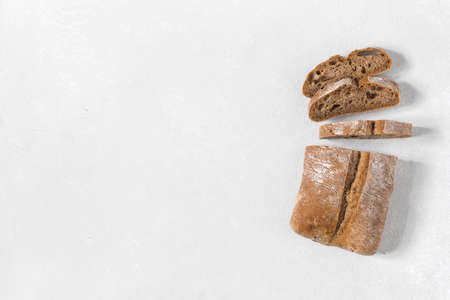 Ciabatta. Dark fresh healthy flattish open-textured Italian bread with a floury crust made with olive oil on white rustic background. Close-up. Top viewの写真素材