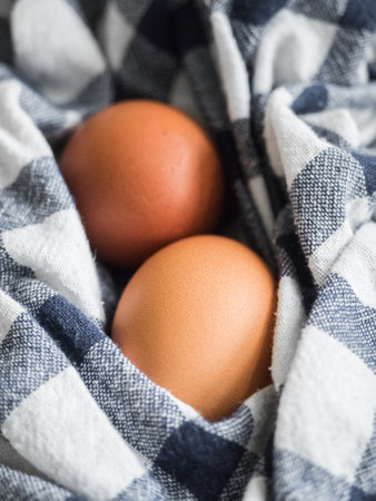 Two beige chicken eggs lie on a checkered mat. Healthy food vertical background. Easter concept. Close-upの写真素材