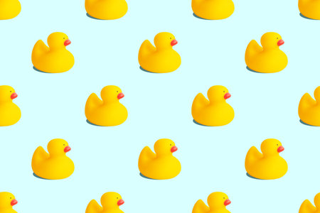 Yellow rubber duck toys seamless pattern isolated on pastel blue background. Opposition symbol and political struggle minimal conceptの写真素材