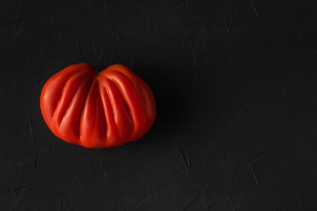 Big tasty ripe ugly farm tomatoes on black background. Natural healthy vegetables concept. Minimalistic food composition flat layの写真素材