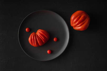 Big tasty ripe ugly farm tomatoes on black background. Natural healthy vegetables concept. Minimalistic food composition flat layの写真素材