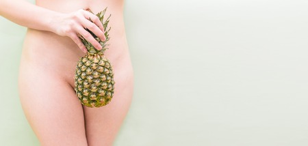 Naked girl covers herself with pineapple. Womens bikini area. Cosmetology and Medicineの写真素材