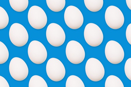 White eggs on a blue background. Many eggs arranged in a row. View from above