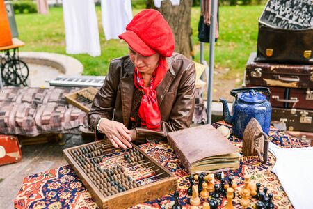 Russia, city Moscow - September 6, 2014: A woman with a leather jacket and a red beret counts on a counting board. Counting board with bones on the table. Old wooden abacus. Retro calculatorのeditorial素材