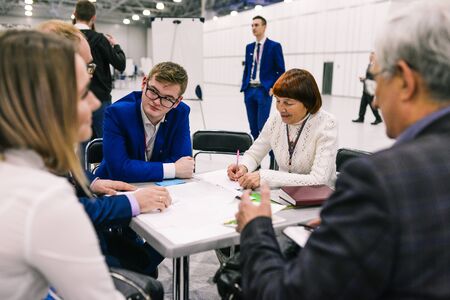 Russia, city Moscow - December 18, 2017: Men and women condemn the project at the meeting. Startup businessmen are discussing a business project. Team work at the tableのeditorial素材