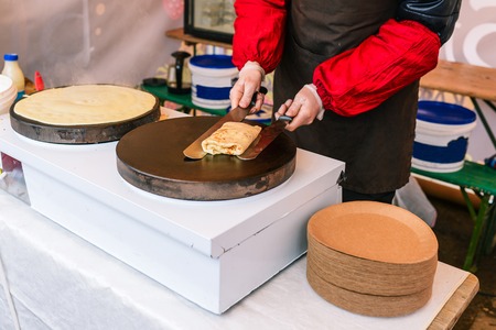 Man prepares pancakes on the stove. A man wraps a stuffed pancake. Cooking outside. Chef bakes fresh pancakesの写真素材