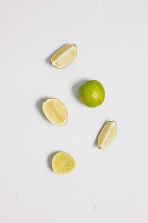 Sliced lime slices arranged in a row on a white background. Fresh citrus fruits. Minimal style, art gallery. Healthy foodの写真素材