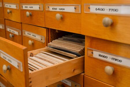 Files catalog with open drawer. Vintage wood cabinet in the library. Paper cards with information....