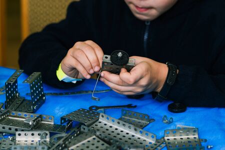 The child collects the constructor. Engineering constructions in miniature. Children's set designer for boys. The development of motor skills of hands, thinking, memory and imagination in a childの写真素材