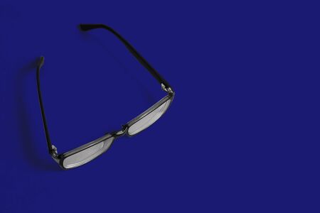 Black glasses on a phantom blue background with black and white lenses. Creative style, art gallery