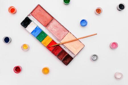 Palette with paints and brush on a white background. Colored small jars of paint. Set of artist for make-up and drawing. Training in drawing and artの写真素材