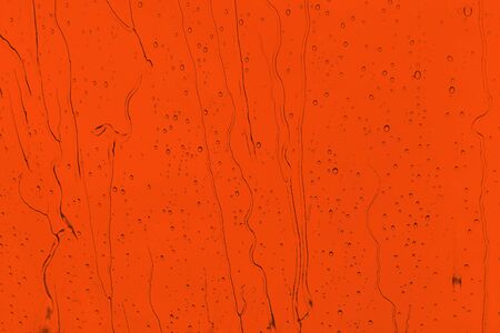 Raindrops on an orange background. Drops of water flow down the surface. The intensity of the red color Lush Lavaの写真素材