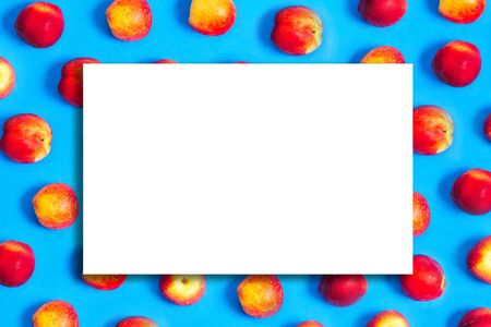 Peaches background with white frame for text. Flat lay of ripe peaches on a blue background. Summer fruits and healthy foodの写真素材