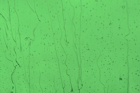Abstract green background with raindrops. Raindrops and water jets on a green background. Bright empty background with textureの写真素材