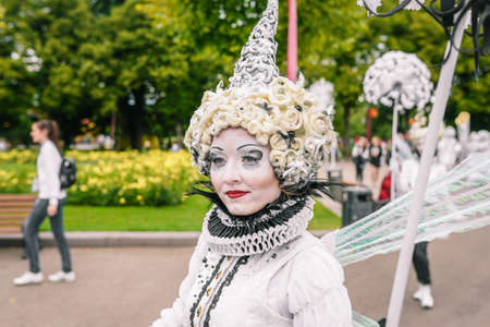 Portrait of a young girl in a white outfit and creative image. Street performer walking on holiday....