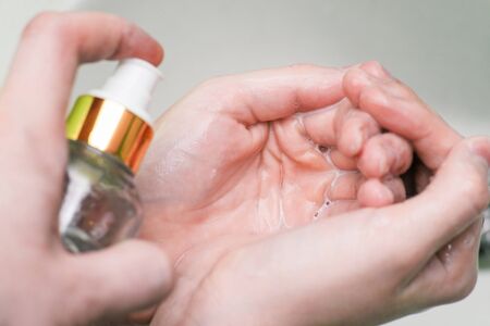 Woman sprays hand antiseptic in the palm of her hand. Liquid to prevent the spread of bacteria and...