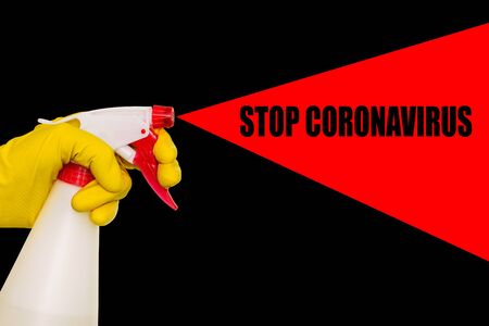 Hand in a yellow glove with a disinfectant on a black background. Poster with text stop coronavirusの写真素材