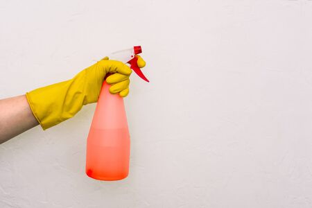 Worker's hand in a yellow glove with a red spray gun on a white background. Protection against germs, bacteria and viruses. Prevention of infectious diseasesの写真素材